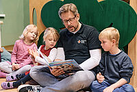 Das Foto zeigt einen DRK Helfer, der Kindern vorliest