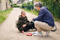 Das Foto zeigt einen Ersthelfer, der sich um eine gestürzte Fahrradfahrerin kümmert.