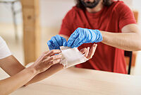 Das Foto zeigt einen Ersthelfer, der einen Verband anlegt.