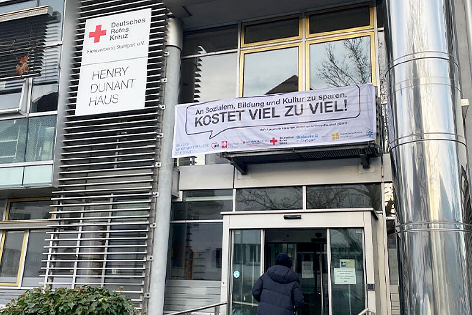 Eingang mit Banner gegen Kürzungen