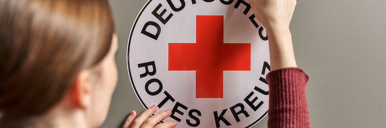 Das Foto zeigt eine Frau, die einen DRK Aufkleber aufklebt