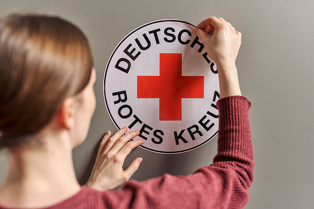 Das Foto zeigt eine Frau, die einen DRK Aufkleber aufklebt
