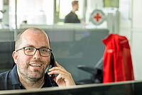 Das Foto zeigt einen telefonierenden DRK Mitarbeiter