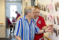 Das Foto zeigt eine Bewohnerin mit einer Pflegekraft, die sich gemeinsam Fotos anschauen.