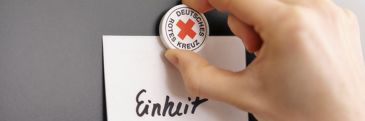 Das Foto zeigt einen DRK Magnet, der das Wort "Einheit" anpinnt.